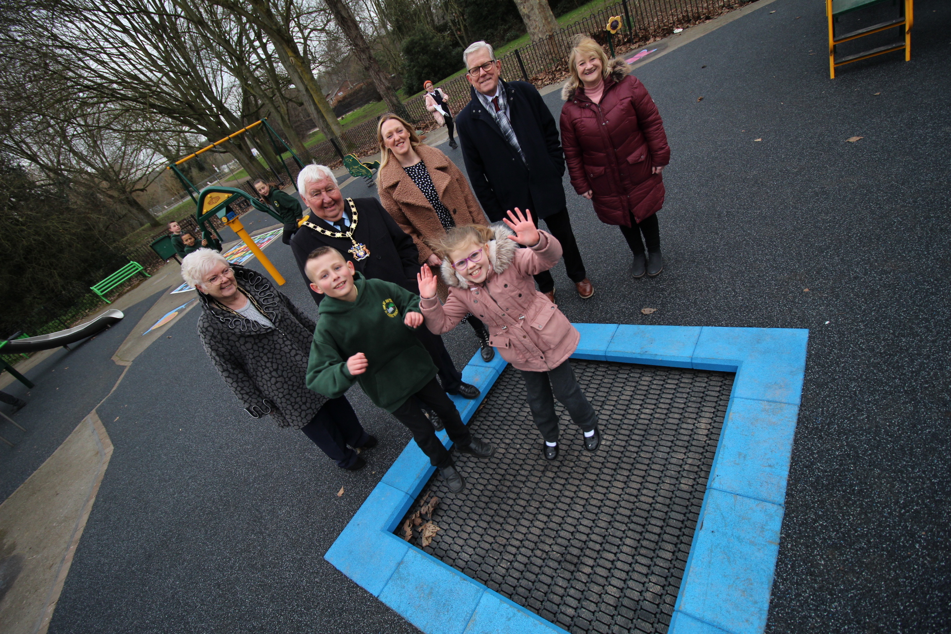 Children jumping on trampoline with Mayor in background